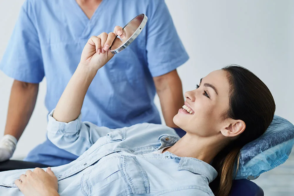 Patient holding a mirror in a dental treatment chair.